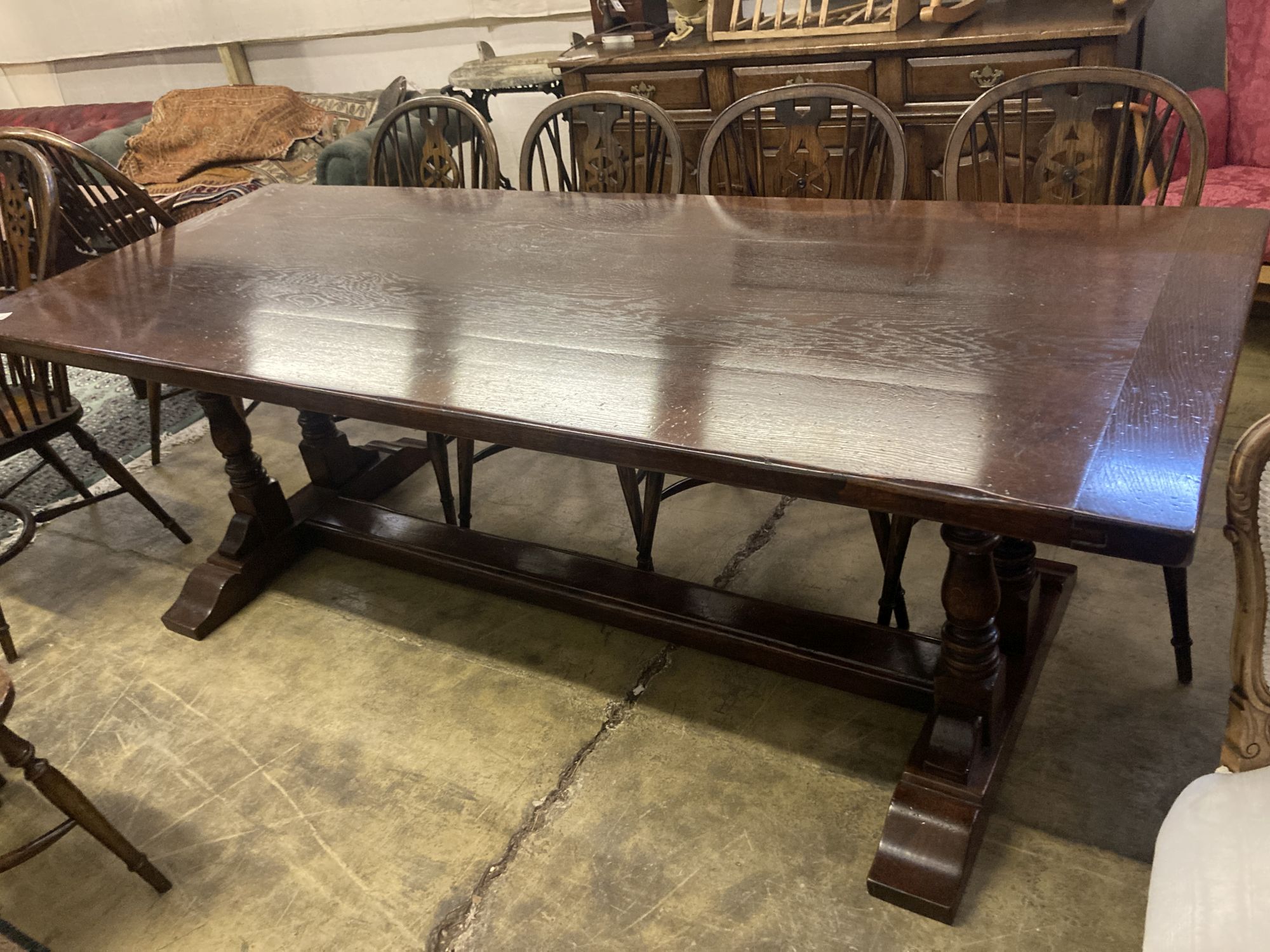 An 18th century style oak refectory table having planked top on double turned end supports, width 230cm depth 90cm height 76cm